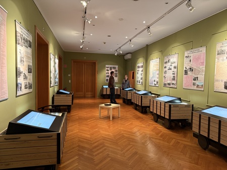 Pogled na razstavo, ki jo tvori osem rudarskih vozičkov z zasloni